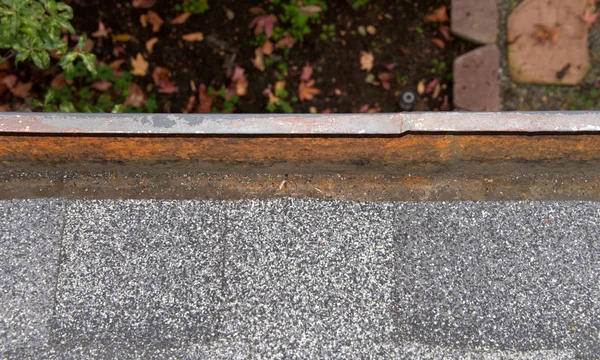Close up on section of rain gutter on residential home, clean and uncovered. Debris like leaves, twigs can clog your gutter system, causing potential harm to your house, landscaping and the gutters.