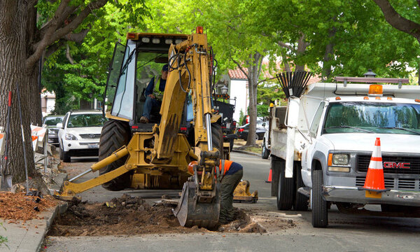 Аламеда, Калифорния - 11 июля 2018 года: Окружные рабочие бригады ремонтируют дороги, поврежденные корнями деревьев. Корневой подъем, иногда называемый тротуарным подъемом, вызывается корнями деревьев, которые не имеют достаточного места для роста
.