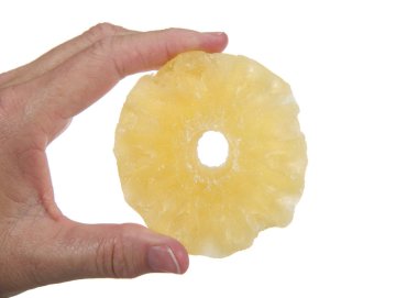 Bir adet şekerli ananas dilimi beyaz arka planda izole edilmiş yetişkin kadın eliyle tutulmuş. Sağlıklı, lezzetli, besleyici ikram..
