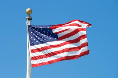 Rüzgarda dalgalanan Amerikan bayrağı berrak mavi bir arka planda