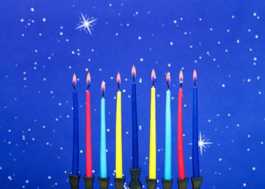 Dokuz dallı bir menorah (Hanukiah ya da Hanukiah olarak da bilinir) mavi yıldızlı arka planda Hanuka 'yı kutlamak için mum yakar..
