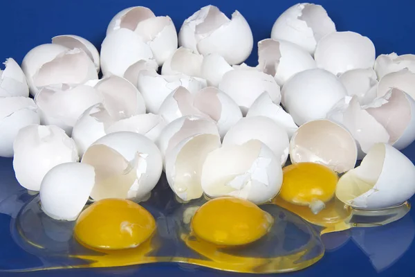 Many broken eggs on a blue reflective table