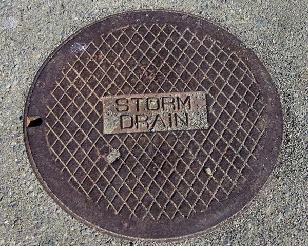 Rustic grunge storm drain manhole cover in concrete