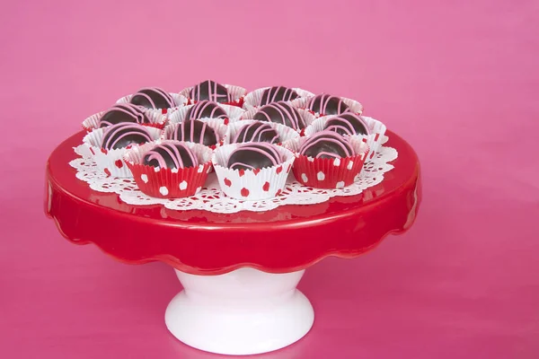 Chocolate cake balls in red and white dot liners on red plate pi — Stock Photo, Image