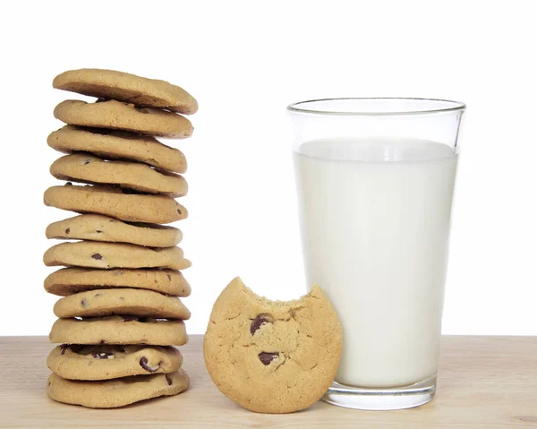 Pila di 12 biscotti al cioccolato accanto a un bicchiere di latte — Foto Stock