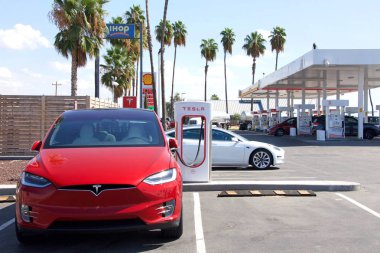 Bakersfield, CA - Sept 28, 2019: Tesla Super Charging station on Stockdale Hwy and 5 fwy. Supercharger stations allow Tesla cars to be fast-charged at the network within an hour. Gas station behind. clipart
