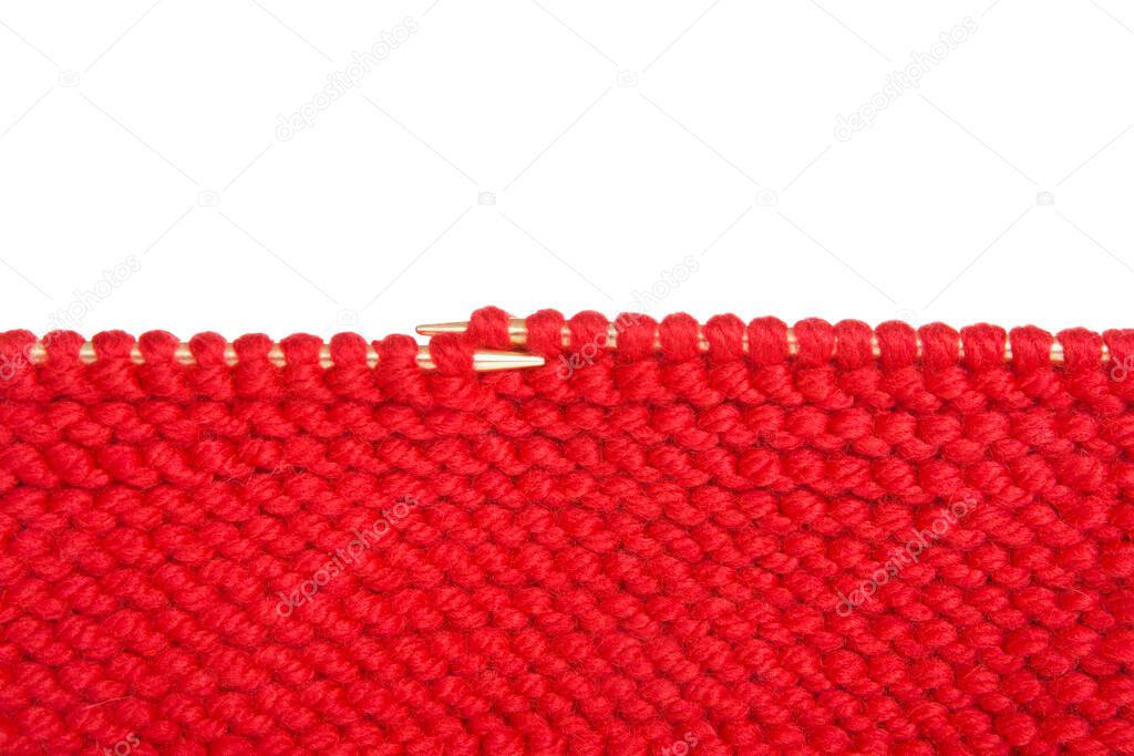 Close up on knitting needles with red yarn project. Isolated on white.