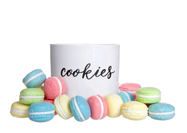 Porcelain cookie jar labeled, with macaron cookies outside the jar in various colors and flavors. Isolated on white.