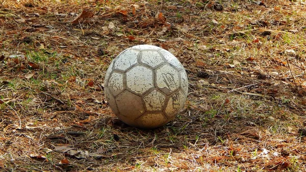 Old soccer ball on the grass on the field — Stock Photo, Image