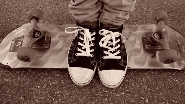 Feet in sneakers are on a skateboard