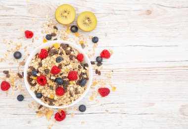 Mısır gevreğiyle kahvaltıda tam tahıl ve çilek, yabanmersini, ahududu ve süt, C vitamini ve ahşap masada sağlıklı yiyecekler karışımı.