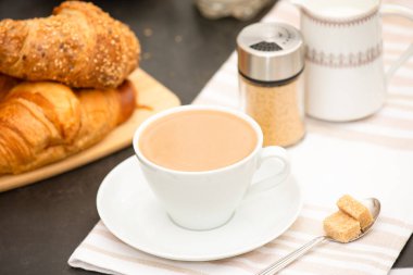 Kahvaltıda sıcak kahve, tereyağlı kruvasan ve şekerli süt. Kahvaltıyı hazırlıyorum.