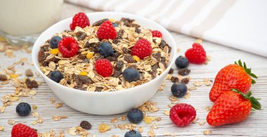 Mısır gevreğiyle kahvaltıda tam tahıl ve çilek, yabanmersini, ahududu ve süt, C vitamini ve ahşap masada sağlıklı yiyecekler karışımı.