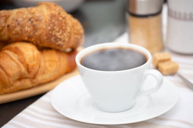 Kahvaltıda sıcak kahve, tereyağlı kruvasan ve şekerli süt. Kahvaltıyı hazırlıyorum.