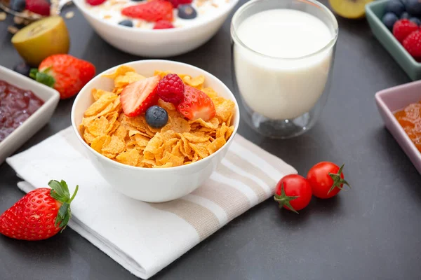 Breakfast with corn flakes mixed with Whole grains and group fruit of Strawberry, Blueberry, Raspberry and Milk, vitamin C and Healthy food on the wood table
