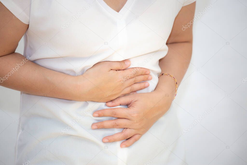 The image of an Asian woman holding her hand in her stomach because of a stomachache, because of a stomachache and having food-borne infections in a white background.