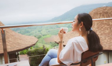 Asyalı bir kadın sabahları evinde, dağların yanında kahve ve sis içer. Phetchabun Eyaleti Khao Kho 'da doğanın tazeliği ve Tayland yemekleri..