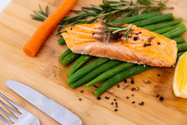 Kızarmış yeşil fasulyeli ızgara somon bifteği, fırında patates, limon ve salata sebzeleri ahşap tabakta diyet yapmak için sağlıklı bir diyettir..