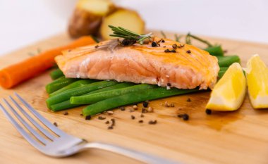 Kızarmış yeşil fasulyeli ızgara somon bifteği, fırında patates, limon ve salata sebzeleri ahşap tabakta diyet yapmak için sağlıklı bir diyettir..