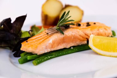 Kızarmış yeşil fasulyeli ızgara somon bifteği, fırında patates, limon ve salata sebzeleri tabakta diyet yapmak için sağlıklı bir diyettir..