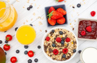 Kahvaltıda yanında tereyağlı kruvasan, mısır gevreği, fincanda süt, çilek, ahududu, kivi, kahvaltı masasında taze portakal suyu....