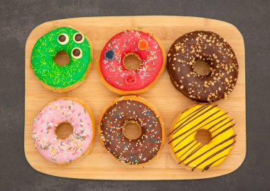 Tatlı, donut, çikolata ve çilek halkaları, şekerli ve kremalı çörekler ve sıcak kahve fincanları, ahşap masa arkasında kırılma veya parti hazırlığı.