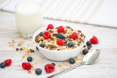 Kahvaltıda mısır gevreği, tam tahıl ve fincanda süt, çilek, böğürtlen, ahududu, ahududu, ahşap masada Kivi, diyet yemeği veya sabahları sağlıklı yemekle servis edilir..