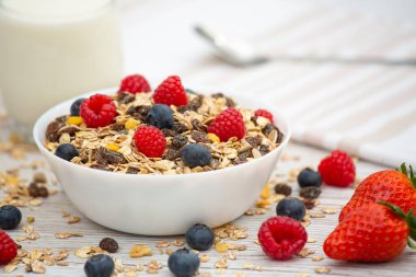 Kahvaltıda mısır gevreği, tam tahıl ve fincanda süt, çilek, böğürtlen, ahududu, ahududu, ahşap masada Kivi, diyet yemeği veya sabahları sağlıklı yemekle servis edilir..