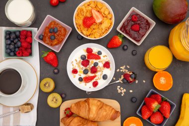 Kahvaltıda yanında tereyağlı kruvasan, mısır gevreği, fincanda süt, çilek, ahududu, kivi, kahvaltı masasında taze portakal suyu....