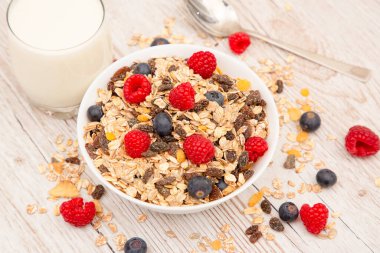 Kahvaltıda mısır gevreği, tam tahıl ve fincanda süt, çilek, böğürtlen, ahududu, ahududu, ahşap masada Kivi, diyet yemeği veya sabahları sağlıklı yemekle servis edilir..