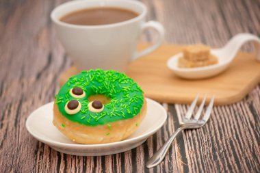 Tatlı, donut, çikolata ve çilek halkaları, şekerli ve kremalı çörekler ve sıcak kahve fincanları, ahşap masa arkasında kırılma veya parti hazırlığı.