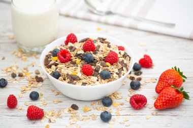 Kahvaltıda mısır gevreği, tam tahıl ve fincanda süt, çilek, böğürtlen, ahududu, ahududu, ahşap masada Kivi, diyet yemeği veya sabahları sağlıklı yemekle servis edilir..