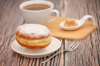 Tatlı, donut, çikolata ve çilek halkaları, şekerli ve kremalı çörekler ve sıcak kahve fincanları, ahşap masa arkasında kırılma veya parti hazırlığı.