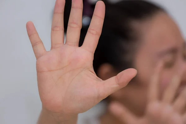 The image of a woman raising her hand to prohibit or cover her face to show resistance and want to stop in the violence of Concept Violence against women in a white background.