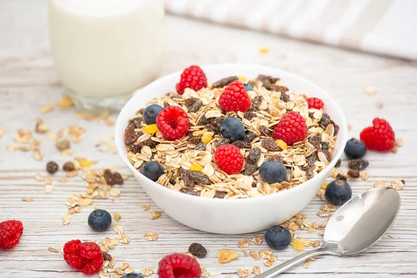 Breakfast Served in the morning with corn flakes Whole grains and raisins with milk in cups and Strawberry, Blueberry, Raspberry, Kiwi on the wood table,Diet food or healthy food in the morning.