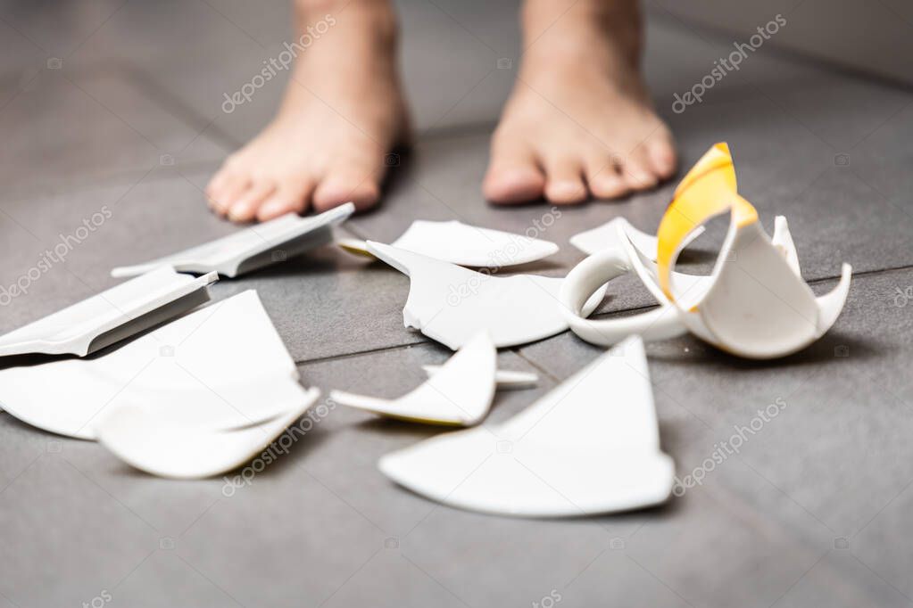 Broken Plate or broken water glass and dishes on the floor in the kitchen room The concept of accidents in the kitchen is dangerous for the body and young children inside the house.