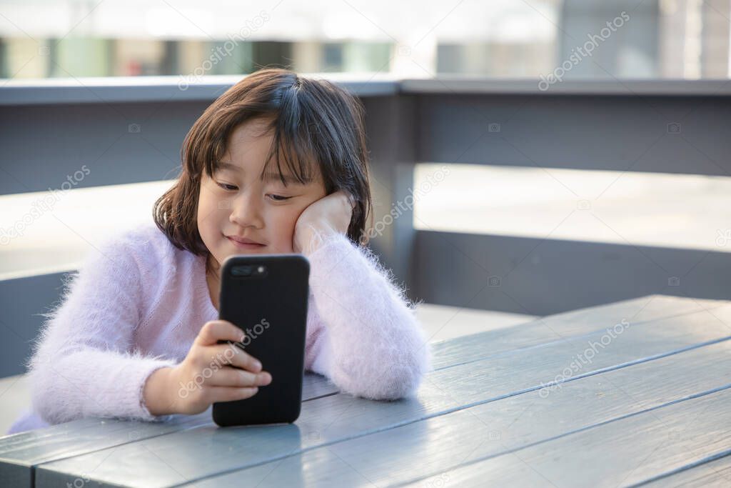 The young girl is watching the phone all day in the house or using a mobile phone for a long time hurts her eyes and has an aggressive atmosphere. Concept danger for children's mobile phone...