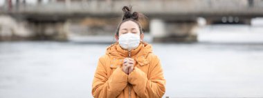 Mikropları, zehirli dumanları ve tozu önlemek için maske takan genç bir Asyalı kadın görüntüsü. Sokaklarda ve bahçelerde bakteriyel enfeksiyonun önlenmesi.