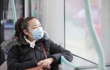 Mikropları, zehirli dumanları ve tozu önlemek için maske takan genç bir Asyalı kadının görüntüsü. Sokaklarda ve bahçelerde bakteriyel enfeksiyonun önlenmesi.