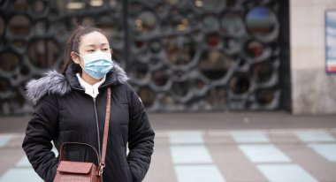 Mikropları, zehirli dumanları ve tozu önlemek için maske takan genç bir Asyalı kadının görüntüsü. Sokaklarda ve bahçelerde bakteriyel enfeksiyonun önlenmesi.