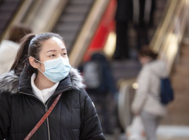 Mikropları, zehirli dumanları ve tozu önlemek için maske takan genç bir Asyalı kadının görüntüsü. Sokaklarda ve bahçelerde bakteriyel enfeksiyonun önlenmesi.