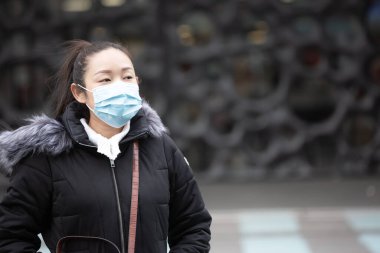 Mikropları, zehirli dumanları ve tozu önlemek için maske takan genç bir Asyalı kadının görüntüsü. Sokaklarda ve bahçelerde bakteriyel enfeksiyonun önlenmesi.