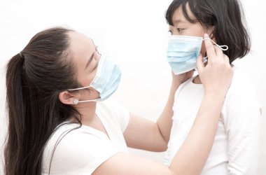 Mikropları, zehirli dumanları ve tozu önlemek için maske takan genç bir Asyalı kadın ve ailenin resmi. Beyaz arka planda havada bakteriyel enfeksiyonun önlenmesi