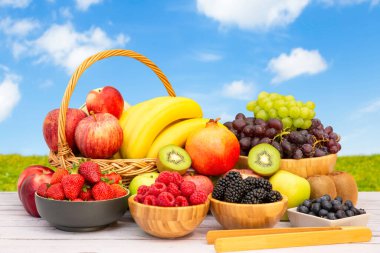 Muz, kivi, üzüm, ahududu, böğürtlen ve böğürtlenli C vitamini ile ahşap sepetteki sağlıklı meyve grubu..