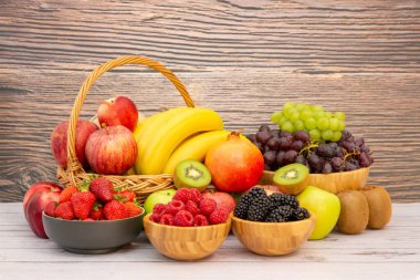 Muz, kivi, üzüm, ahududu, böğürtlen ve böğürtlenli C vitamini ile ahşap sepetteki sağlıklı meyve grubu..