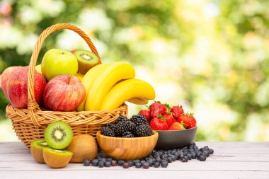 Muz, kivi, üzüm, ahududu, böğürtlen ve böğürtlenli C vitamini ile ahşap sepetteki sağlıklı meyve grubu..