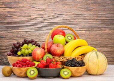 Muz, kivi, üzüm, ahududu, böğürtlen ve böğürtlenli C vitamini ile ahşap sepetteki sağlıklı meyve grubu..
