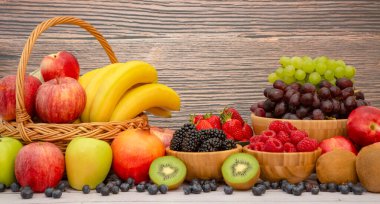 Muz, kivi, üzüm, ahududu, böğürtlen ve böğürtlenli C vitamini ile ahşap sepetteki sağlıklı meyve grubu..