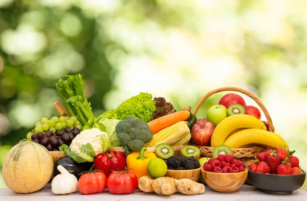 Assortment of Fresh vegetables and fruits With vitamins c from bananas, kiwi, grapes, raspberries, blueberries, and blackberries, good for the body and diet food on the table in nature background.