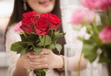 Kırmızı ve pembe gülleri budamaya hazırlanan bir kadın ve evdeki güzel çiçek aranjmanları, masadaki aile içinde Sevgililer Günü ve İş için vazo ile çiçek aranjmanları.